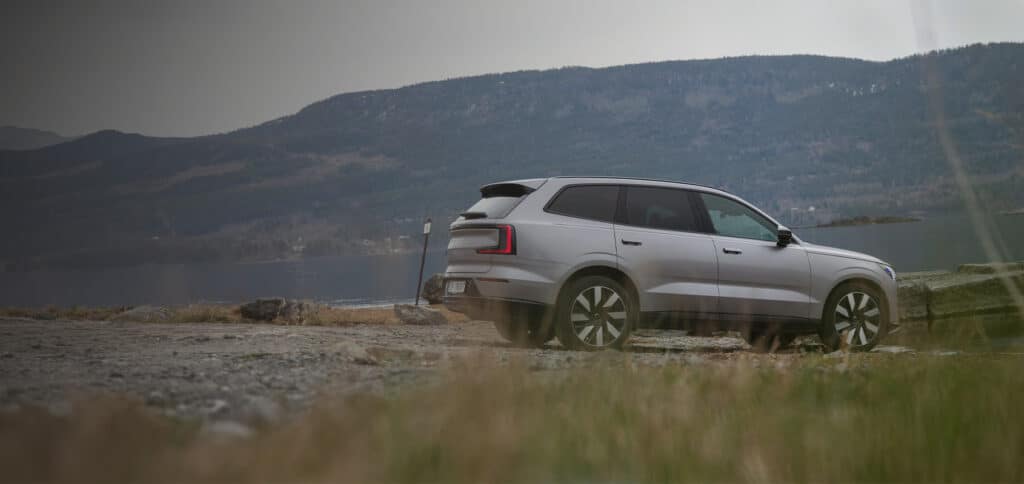 Sølvgrå Volvo EX90 parkert ved fjord og fjell