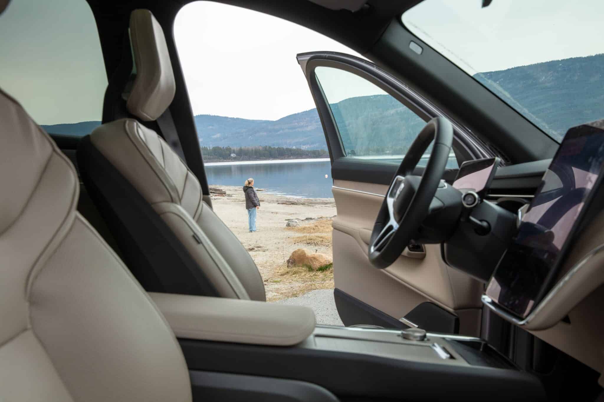 Interiør i Volvo EX90 med lyse seter og utsikt mot fjordlandskap