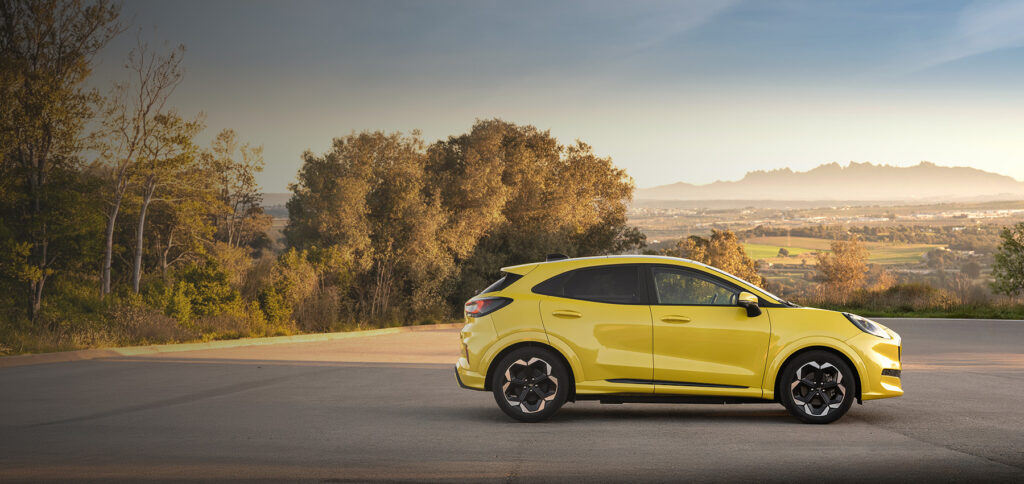 Gul Ford Puma parkert med utsikt over landskap og fjell