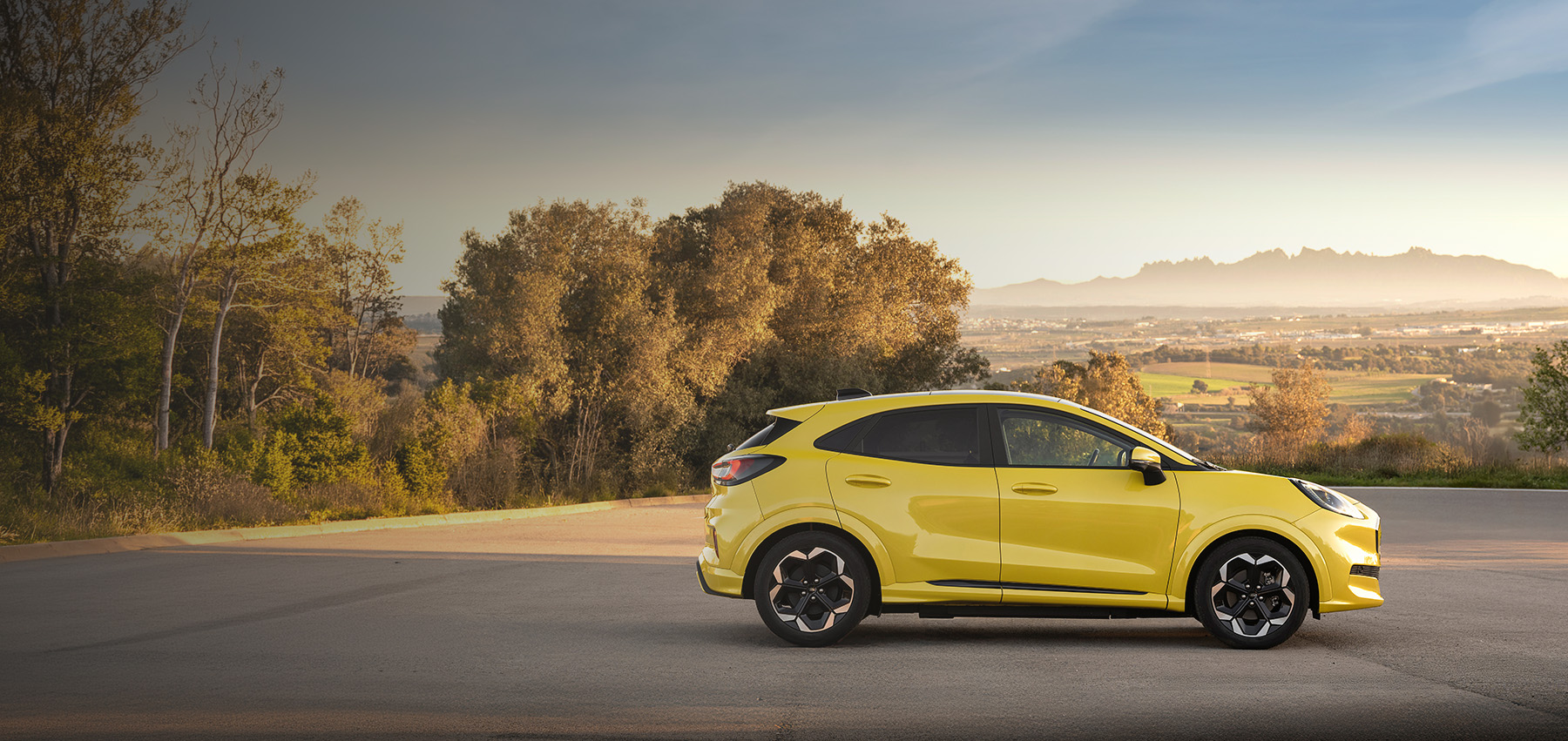 Gul Ford Puma parkert med utsikt over landskap og fjell