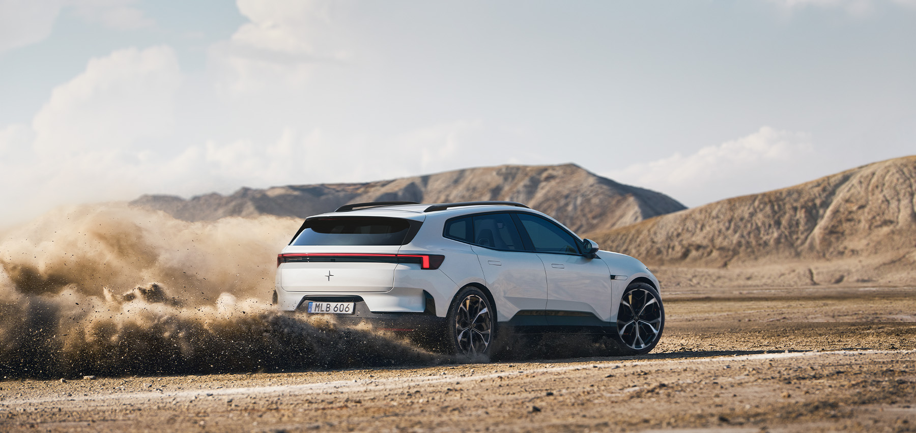 Hvit Polestar 4 SUV kjører på grusvei i åpent landskap