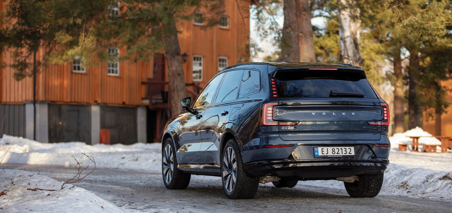 Volvo EX90 bakfra foran norsk trehus om vinteren